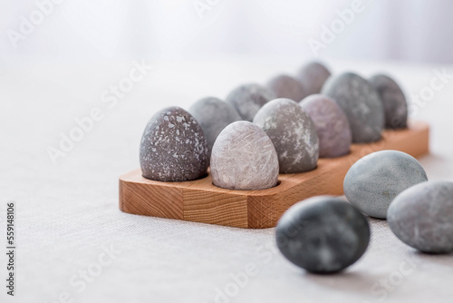 Stylish grey Easter eggs in marble and concrete on a wooden stand. Coloring eggs with natural dye karkade tea. Environmental friendliness. Naturalness. The concept of happy Easter 2023.