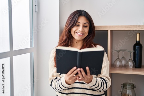 Young hispanic woman smiling confident reading book at home
