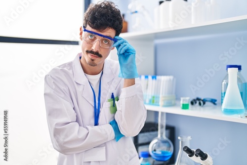 Young caucasian man scientist standing with relaxed expression at laboratory