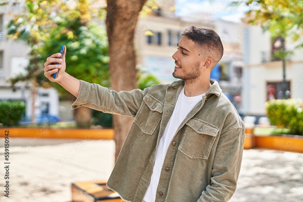 Young hispanic man smiling confident making selfie by the smartphone at park