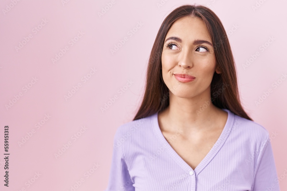 Young hispanic woman with long hair standing over pink background smiling looking to the side and staring away thinking. Young hispanic woman with long hair standing over pink background smiling looking to the side and staring away thinking.