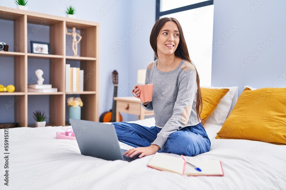 Young beautiful hispanic woman student drinking coffee studying on bed at bedroom Young beautiful hispanic woman student drinking coffee studying on bed at bedroom