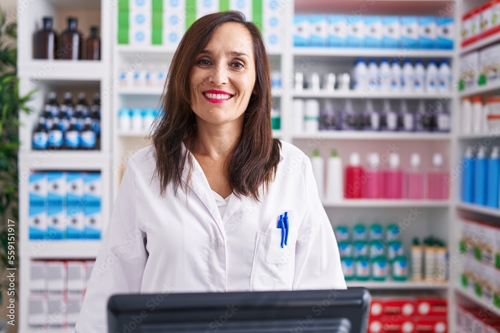 Middle age brunette woman working at pharmacy drugstore with a happy and cool smile on face. lucky person.