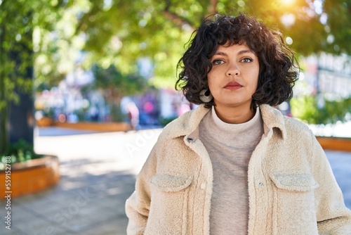 Young beautiful hispanic woman standing with serious expression at park photo