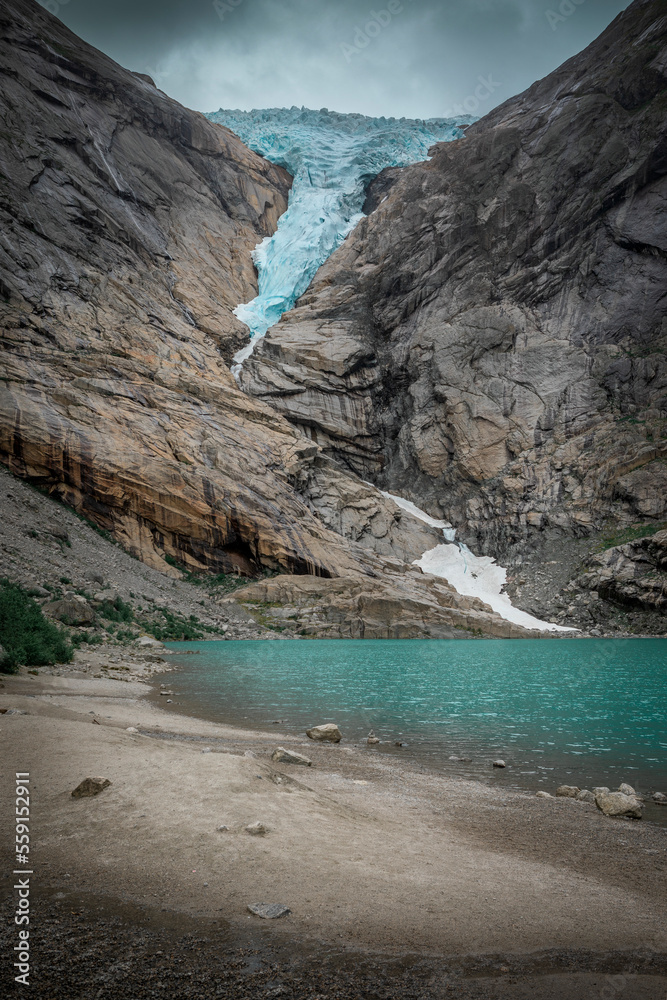 Obraz premium Briksdalsbreen glacier in the mountains of Jostedalsbreen national park in Norway, turquoise glacier lake and blue ice, rocks along the beach