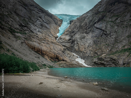 Briksdalsbreen glacier in the mountains of Jostedalsbreen national park in Norway, turquoise glacier lake and blue ice, rocks along the beach photo