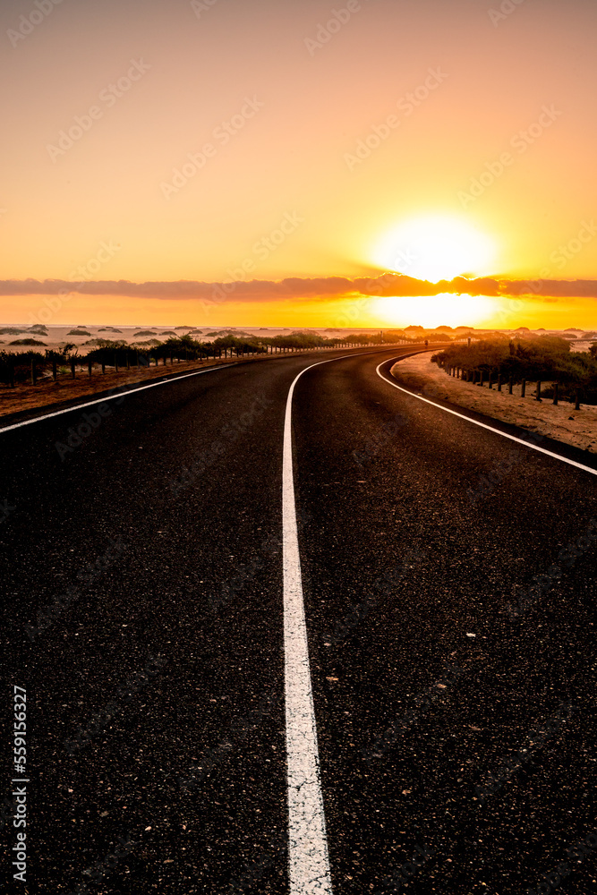 Beautiful morning on a road through the dunes. Sunrise over a road with clouds. Corralejo National Park, Canary Islands, Spain