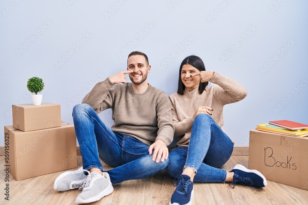 Young couple moving to a new home pointing with hand finger to face and nose, smiling cheerful. beauty concept Young couple moving to a new home pointing with hand finger to face and nose, smiling cheerful. beauty concept