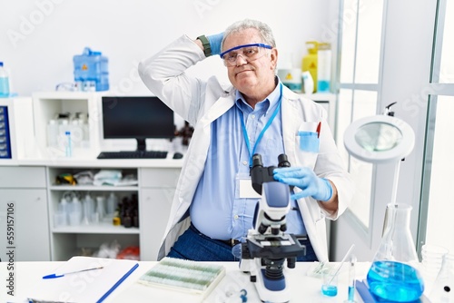 Senior caucasian man working at scientist laboratory smiling confident touching hair with hand up gesture  posing attractive and fashionable