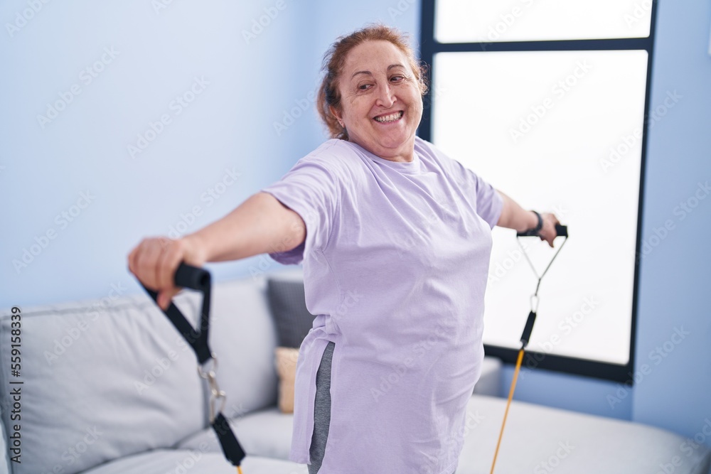 Senior woman smiling confident using elastic band training at home Senior woman smiling confident using elastic band training at home