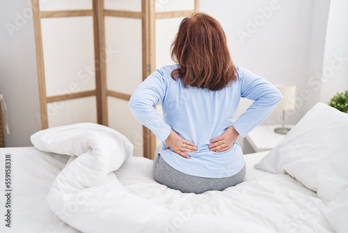Senior woman suffering for backache sitting on bed at bedroom