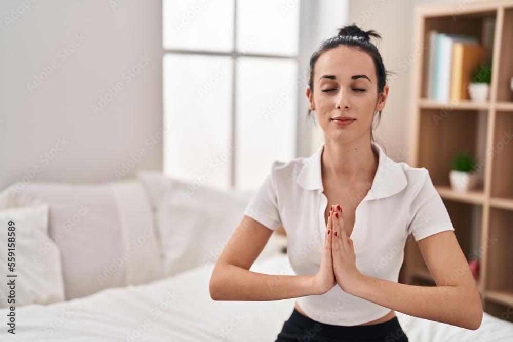 Young caucasian woman doing yoga exercise sitting on bed at bedroom Young caucasian woman doing yoga exercise sitting on bed at bedroom