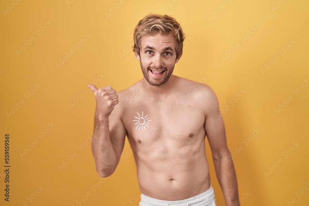 Caucasian man standing shirtless wearing sun screen doing happy thumbs up gesture with hand. approving expression looking at the camera showing success.