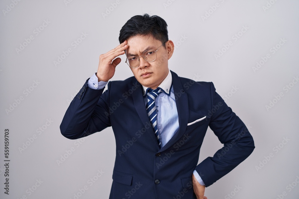 Young asian man wearing business suit and tie worried and stressed about a problem with hand on forehead, nervous and anxious for crisis Young asian man wearing business suit and tie worried and stressed about a problem with hand on forehead, nervous and anxious for crisis