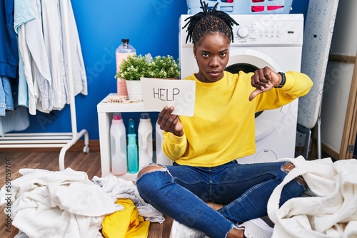 Beautiful black woman doing laundry asking for help with angry face, negative sign showing dislike with thumbs down, rejection concept