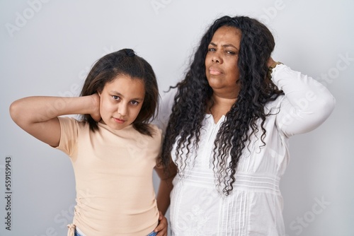 Mother and young daughter standing over white background suffering of neck ache injury  touching neck with hand  muscular pain