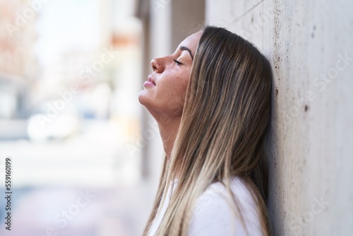 Young beautiful hispanic woman breathing with closed eyes at street