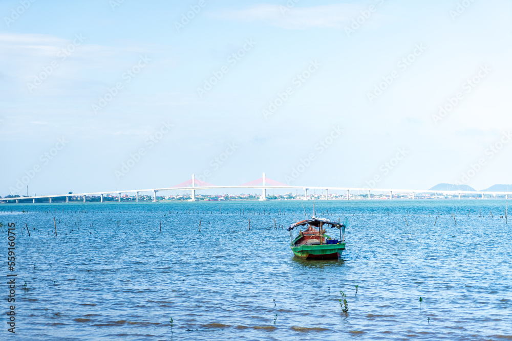 Obraz premium The scenery of the estuary with the bridge crossing is very beautiful, the sky is clear and the small boats are ready to go fishing