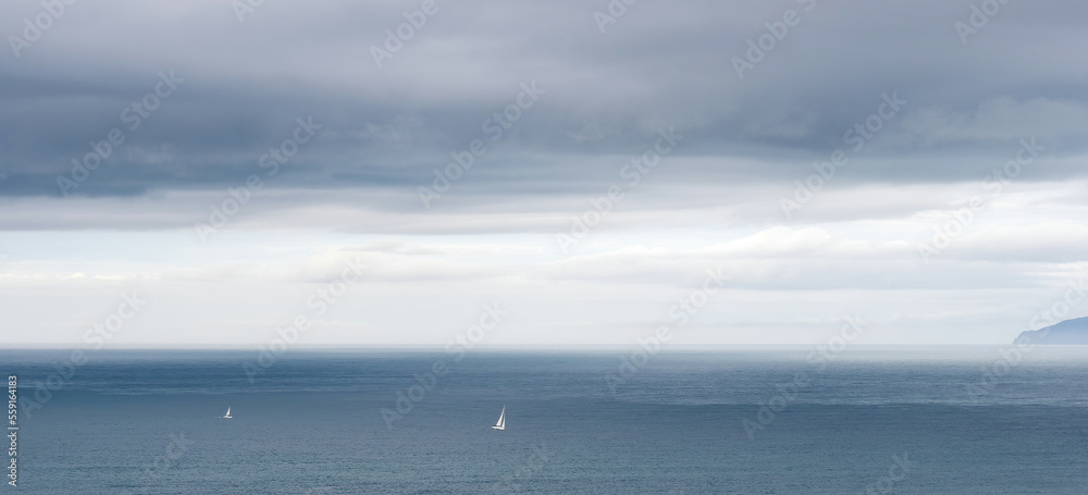 Two yachts with white sails on cloudy evening
