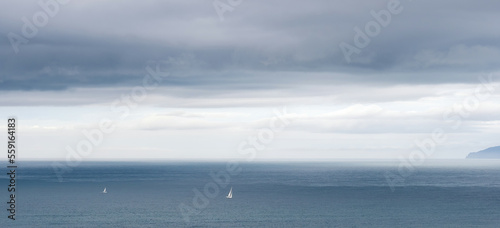 Two yachts with white sails on cloudy evening