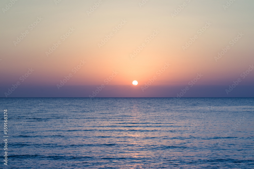 Beautiful sunrise at sea. Dawn on the Red Sea. The sun is reflected in the sea. Palm trees and palm leaves against the background of the rising sun. Tropical sunrise
