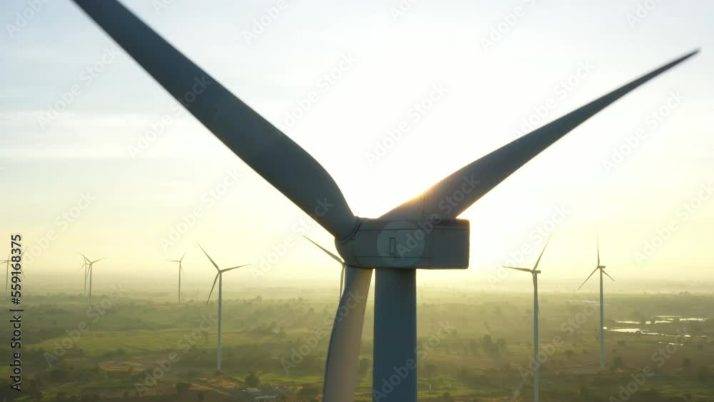 Wind electric generator in the rising sun. Wind generators stand in agricultural fields with Powerful wind turbine farms for pure energy production on the background.