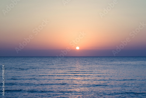 Beautiful sunrise at sea. Dawn on the Red Sea. The sun is reflected in the sea. Palm trees and palm leaves against the background of the rising sun. Tropical sunrise