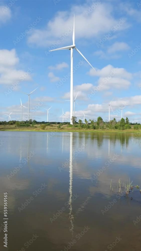 Time Lapse of Powerful Wind turbine farm for pure energy production on Beautiful clear blue sky with white clouds and wind turbine farm reflection on lake. renewable energy. Hyperlapse View Time Lapse of Powerful Wind turbine farm for pure energy production on Beautiful clear blue sky with white clouds and wind turbine farm reflection on lake. renewable energy. Hyperlapse View