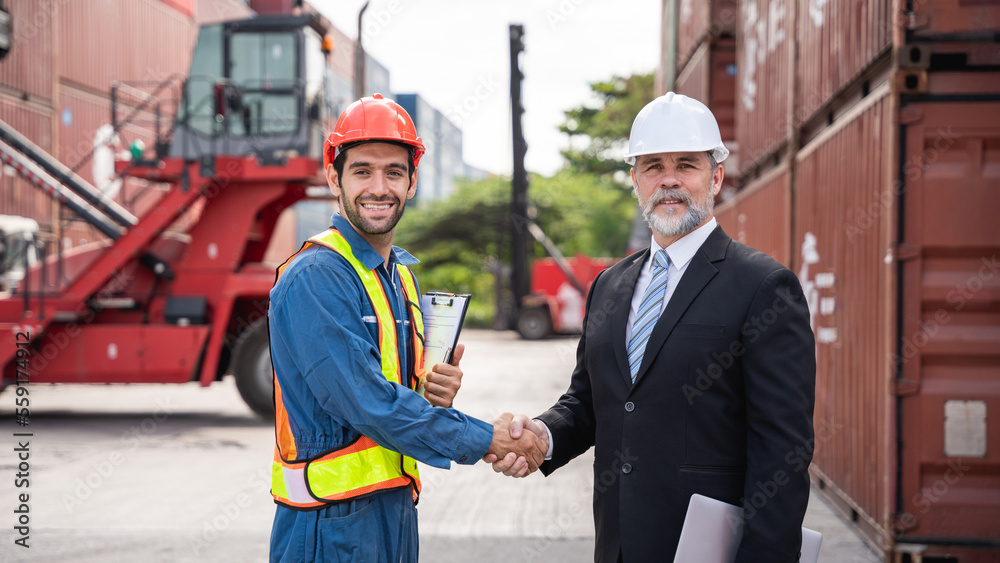 Engineer and foreman shake hand at container yard near with a forklift., Logistics concept inside the shipping, import, and export industries.. Engineer and foreman shake hand at container yard near with a forklift., Logistics concept inside the shipping, import, and export industries..