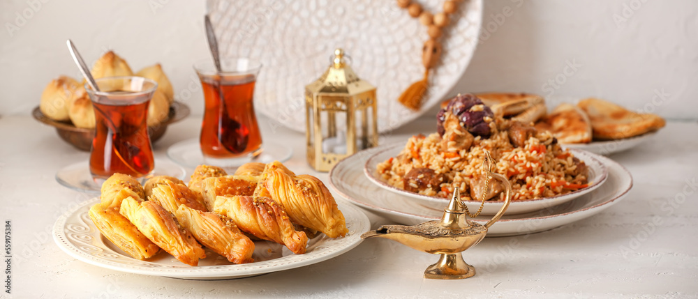 Traditional Eastern dishes with Aladdin lamps and tea on white table Traditional Eastern dishes with Aladdin lamps and tea on white table