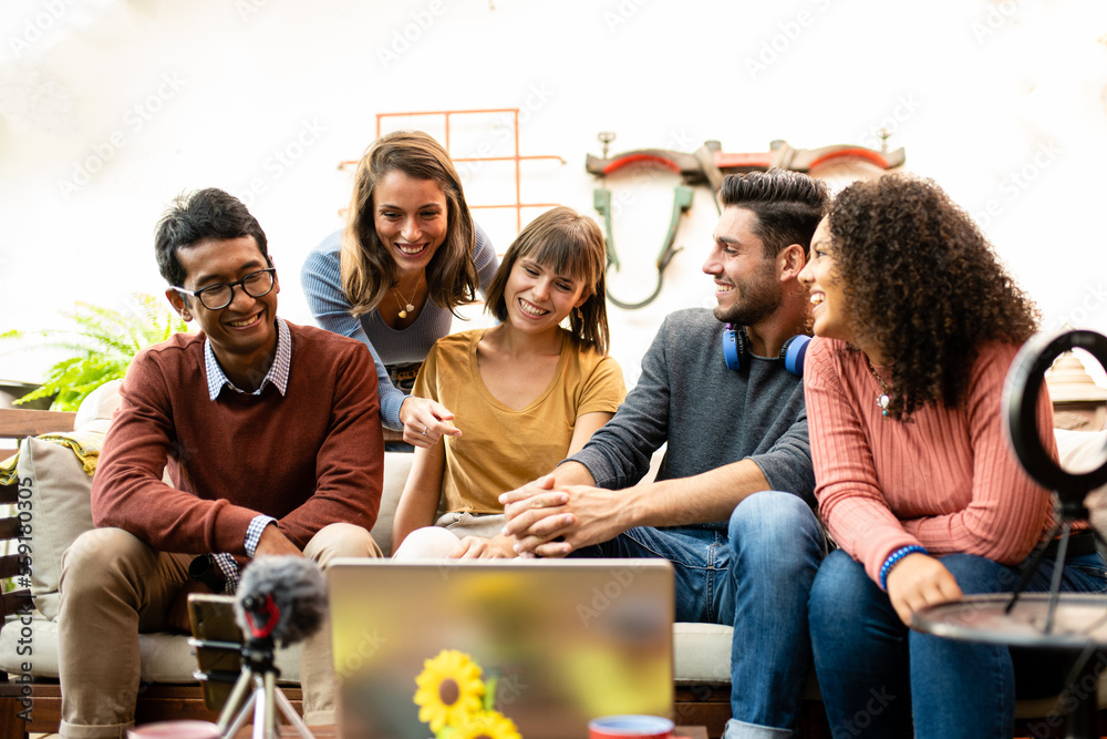 group of young people sharing contents and interview with webcam and laptop, influencers and vloggers having fun on live streaming, happy coworkers of a small business talking and planning - obrazy, fototapety, plakaty 