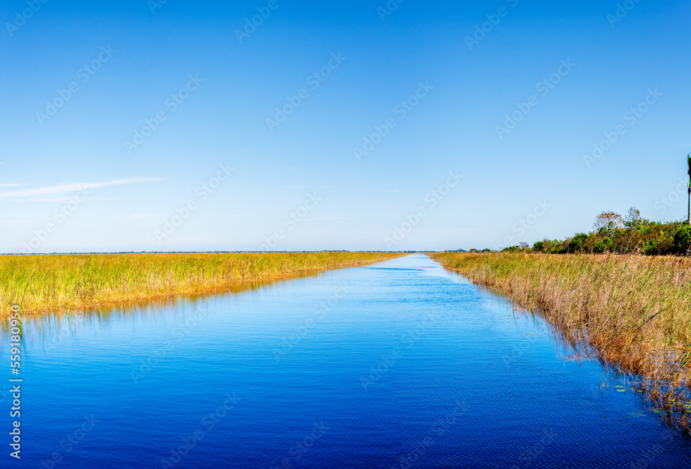 Fototapeta premium river with dry grassy field with blue sky