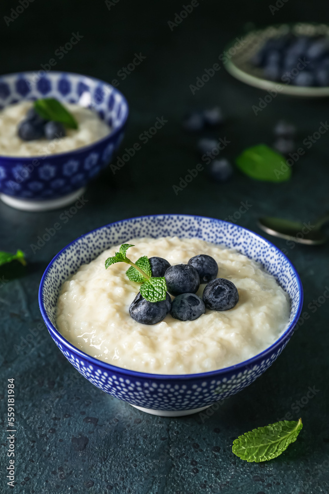 Bowl with delicious rice pudding and blueberries on black background Bowl with delicious rice pudding and blueberries on black background