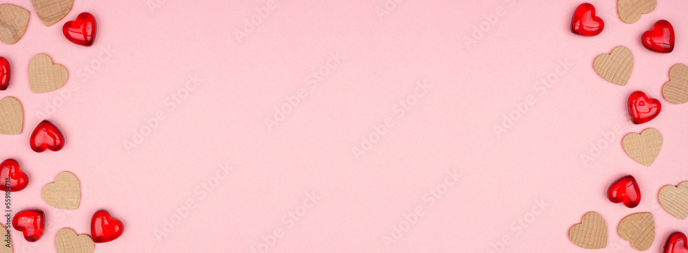 Valentines Day double border of wooden hearts and gems. Overhead view on a soft pink banner background. Copy space.
