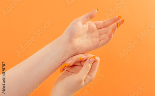 female hand with manicure on orange background