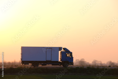 Fotografi Cargo truck driving on highway hauling goods in evening
