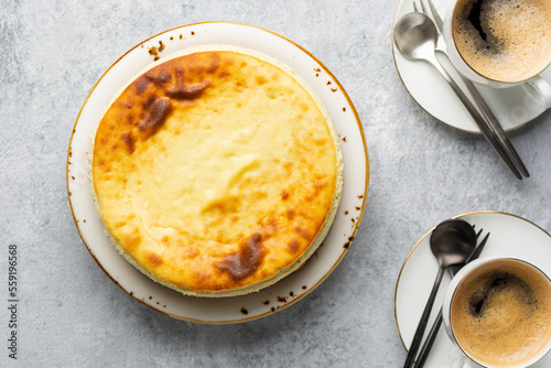 Breakfast concept. Top view of acottage cheese casserole with cups of coffee on a concrete light gray background. Coffee break with cheesecake.