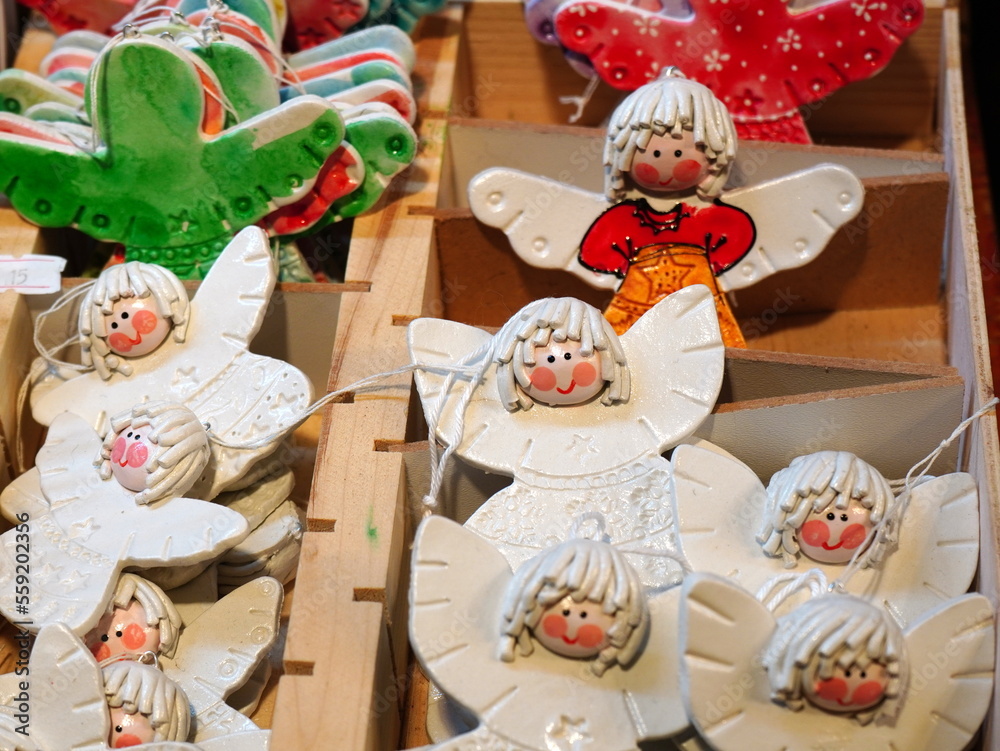 Handmade painted ceramics angel figurines displayed in wooden box for sale as Christmas tree decorations at Christmas market in Bucharest