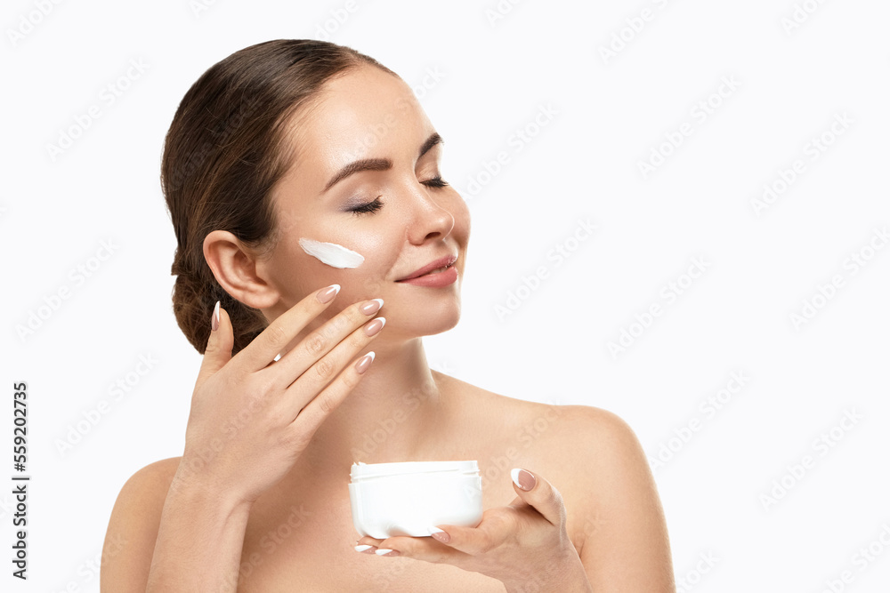 Beautiful Woman Face Skin Care. Portrait Of Attractive Young Female Applying And Holding Cream Cosmetics And Holding Bottle. Closeup Of Beauty Smiling Girl With Natural Makeup And Fresh Skin. Beautiful Woman Face Skin Care. Portrait Of Attractive Young Female Applying And Holding Cream Cosmetics And Holding Bottle. Closeup Of Beauty Smiling Girl With Natural Makeup And Fresh Skin.