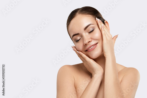 Beautiful Young Woman with Clean Fresh Skin touch own face. Facial  treatment. Skin care. Cosmetology, beauty  and spa.