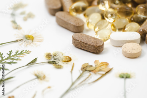 Medicinal capsules with dried medicinal herbs on white background. Herbal medicine  homeopathy  alternative medicine  organic pharmacy concept. Naturopathy and dietary supplement. Herbal plants