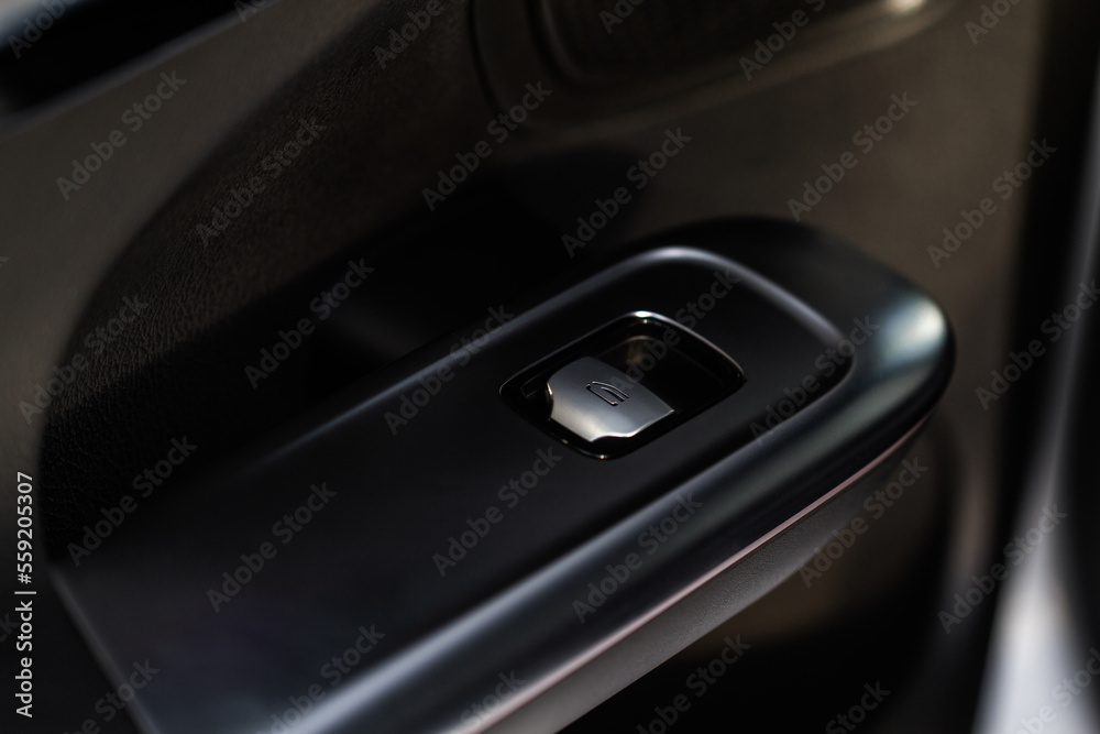 Close up view of button controlling window in modern car interior. Vehicle interior detail. Door handle with windows controls