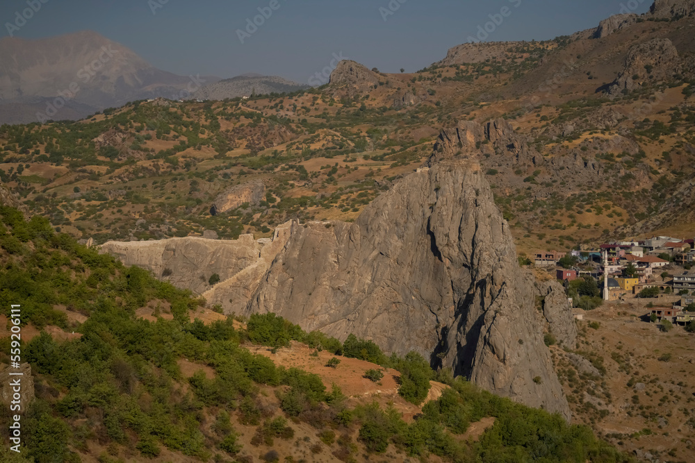 View of Yeni Kale means new castle in english located on a big rock hill with green forground a town and mountains on background