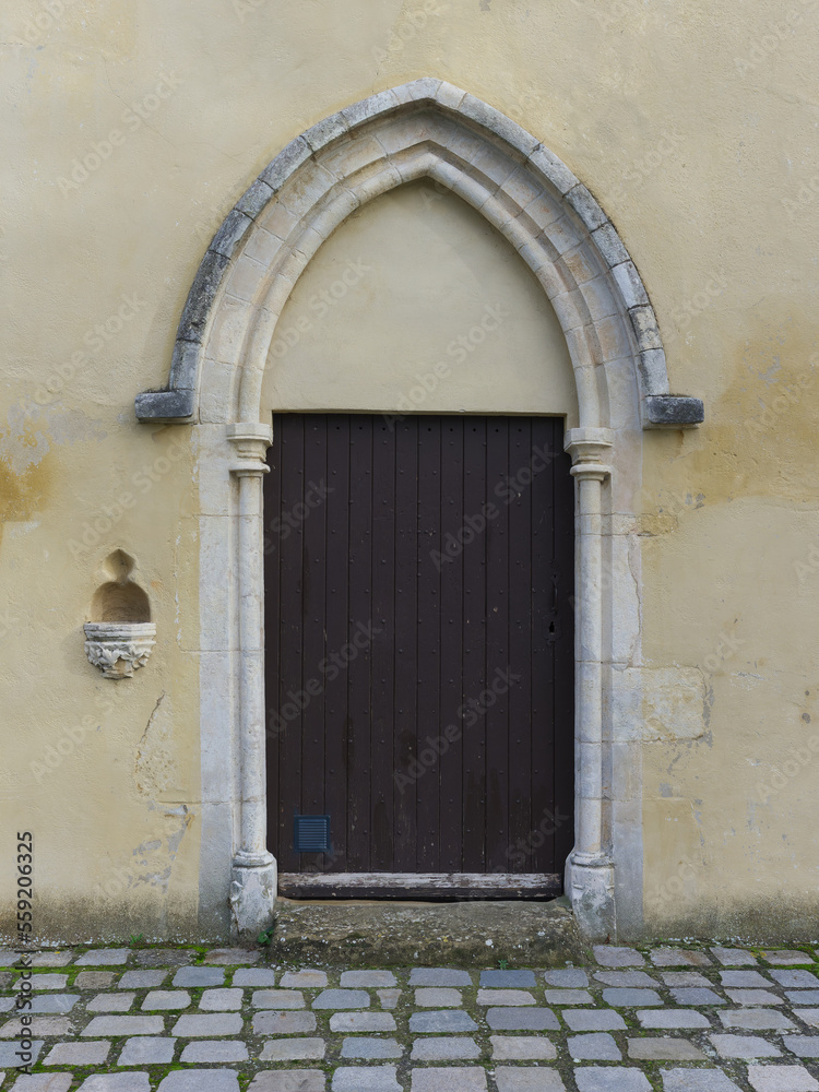 Fototapeta premium Entrance door with holy water stoup of Notre-Dame des Mariniers chapel in Saint Symphorien d'Ozon, France 