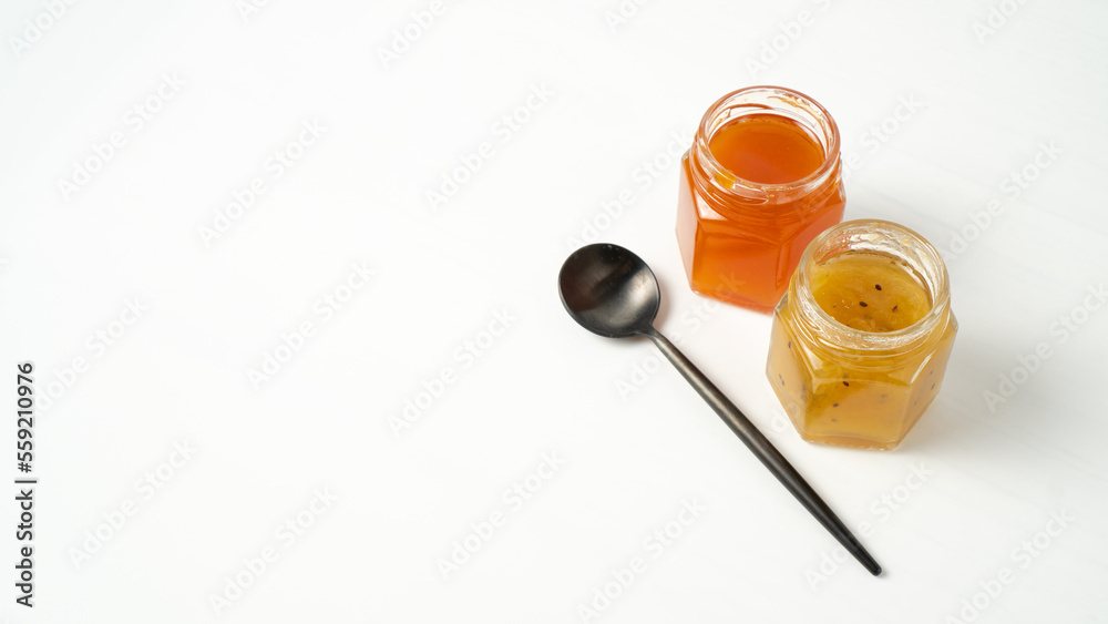 Little jam jars on white background. Small glass jars with passion fruit jam. Apricot marmalade. Coupe of jam jars