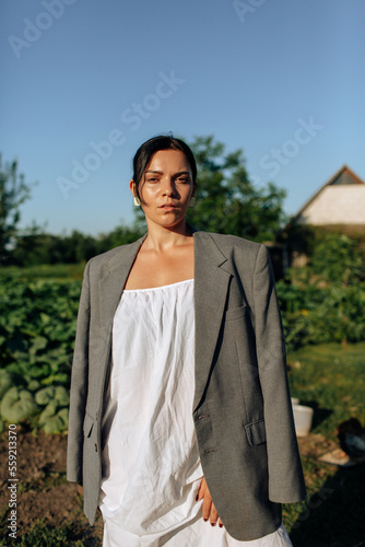 Portrait young beautiful girl in village area. Wooden farm. Backyard. Nature. Yellow grass. Sunset light, autumn. Country style clothes