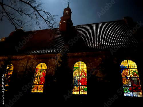 Stained glass window in the church of St. Francis of Assisi in Miotek, Silesia, Poland seen from the outside in the evening. Saint Francis in the foreground photo