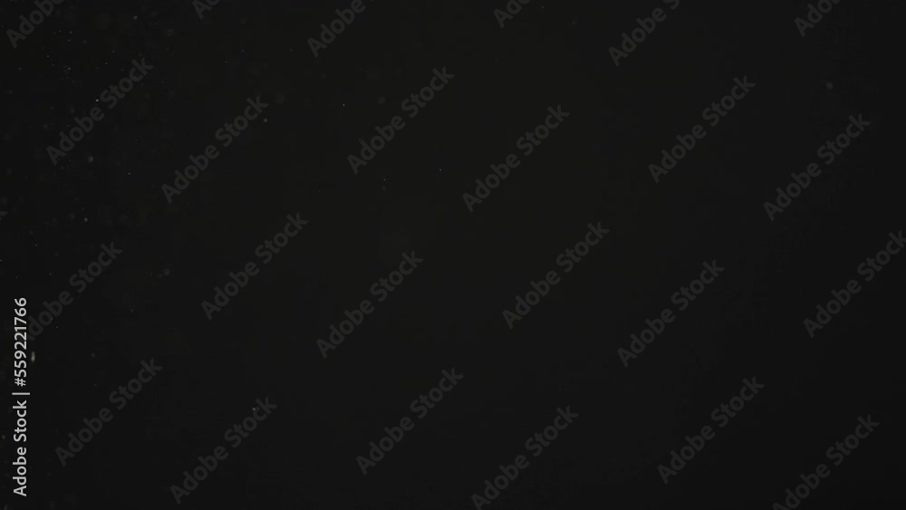 Slow motion real dust particles floating in the air with natural sunlight over black background Slow motion real dust particles floating in the air with natural sunlight over black background