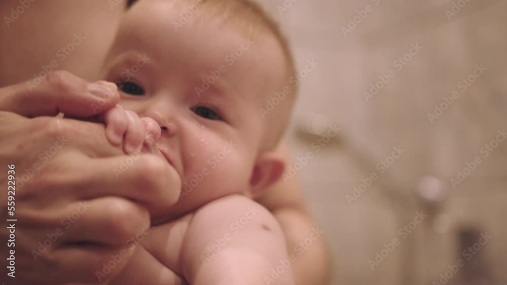 Small child in the arms of his mother is brushing his teeth. Toddler is brushing teeth. Hygiene for babies. A daily ritual Small child in the arms of his mother is brushing his teeth. Toddler is brushing teeth. Hygiene for babies. A daily ritual