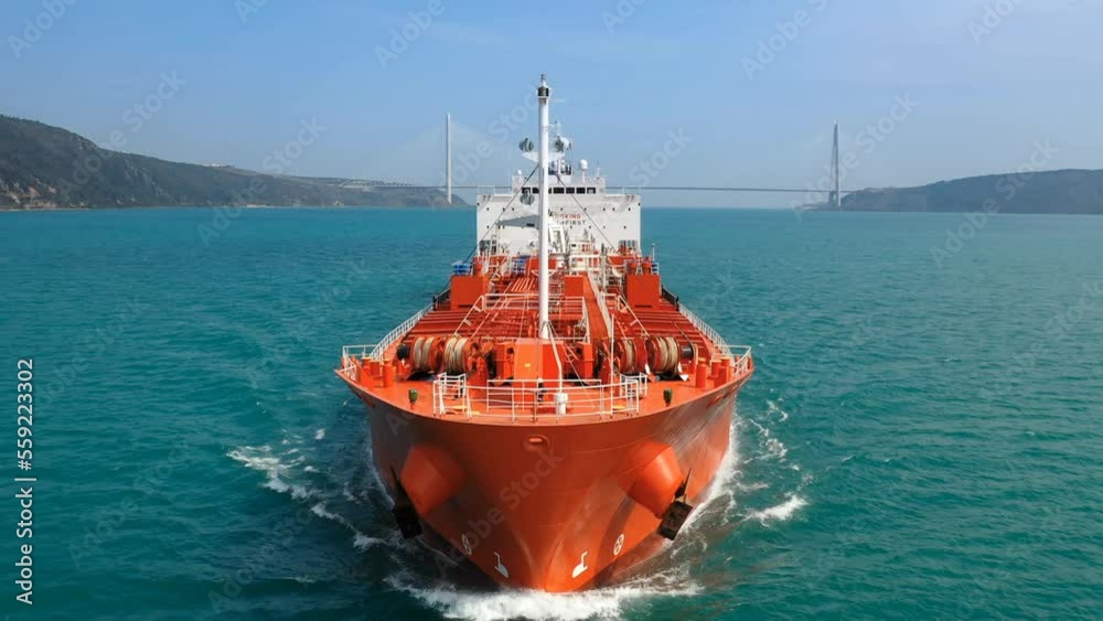Bow and front deck of oil products tanker on ride. Supertanker loaded with full of oil underway in the open sea. Red prow, upper deck, pipe lines and winches of tanker ship cruising in ocean. Slow Mo.